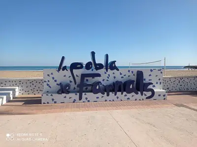 a bench with graffiti on it next to the beach at Fleming's Beach in Puebla de Farnals