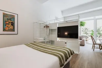 a white bedroom with a large bed with a television at Gran Turia Apartments in Valencia