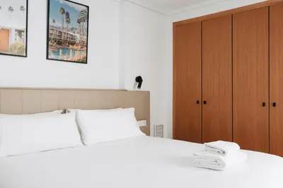 a bedroom with a white bed and a wooden cabinet at White Beach Apartment in Valencia