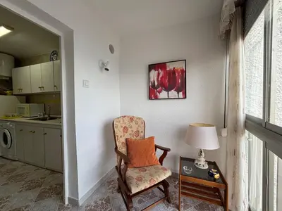 a living room with a chair and a table with a lamp at Relax & Sea View & Beach Access in Faro de Cullera
