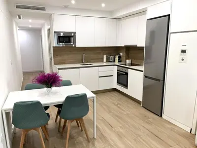 a kitchen with white cabinets and a white table and chairs at Central Market Deluxe Apartments in Valencia