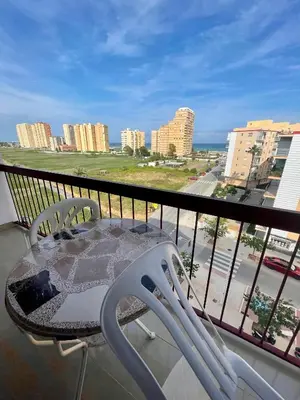 a table and chairs on a balcony with a view of a city at Apto Playa Puebla de Farnals cerca de Valencia in Puebla de Farnals