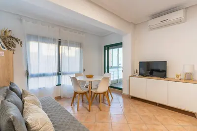 a living room with a couch and a table with chairs at Confortable apto en la playa a 10min de Valencia in Valencia