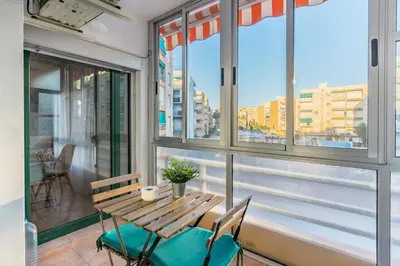 a wooden table and chairs on a balcony with windows at Confortable apto en la playa a 10min de Valencia in Valencia