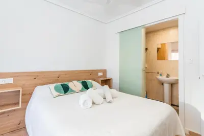 a bedroom with a white bed and a sink at Confortable apto en la playa a 10min de Valencia in Valencia