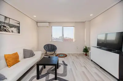 a living room with a white couch and a flat screen tv at Apartamento en el Cabanyal enfrente de la Marina Real in Valencia
