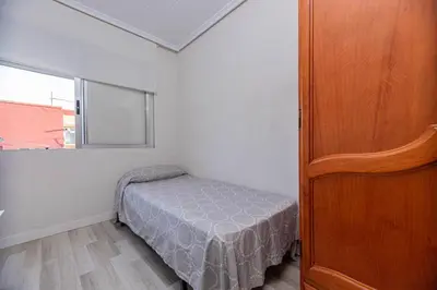 a small bedroom with a bed and a window at Apartamento en el Cabanyal enfrente de la Marina Real in Valencia