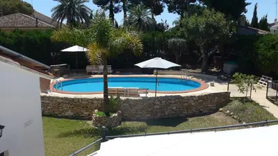 a swimming pool with an umbrella and a stone wall at Casa Kiosko 2 bedroom chalet with swimming pool in La Eliana