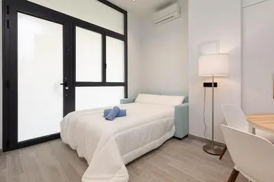 a white bedroom with a bed and a table at Apartamento 3º nuevo a estrenar cerca del mar in Valencia