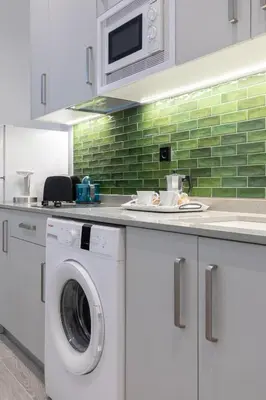 a kitchen with a washing machine and a green tile wall at Apartamento 3º nuevo a estrenar cerca del mar in Valencia