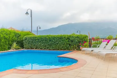 a swimming pool with chairs and a mountain in the background at Luxury villa close to beach, mountain and golf! in Alzira