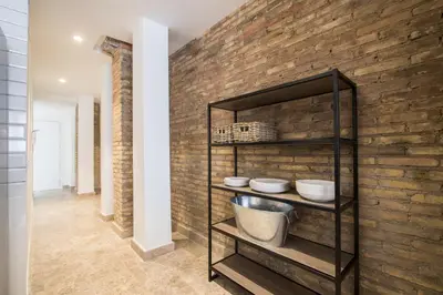 a kitchen with a brick wall and a shelf with dishes at Apartamentos La Marina in Valencia