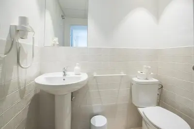 a white bathroom with a sink and a toilet at Apartamentos La Marina in Valencia