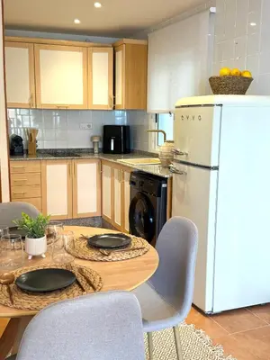 a kitchen with a table and a white refrigerator at Casa Palmera in Sueca