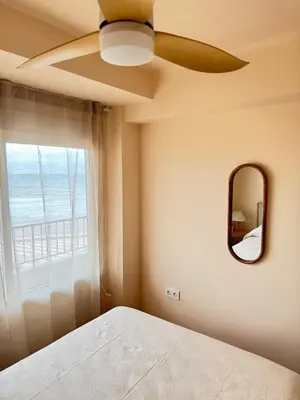 a bedroom with a ceiling fan and a mirror at Casa Palmera in Sueca
