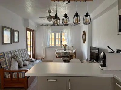 a kitchen and living room with a couch and lights at Parking Privado l Terraza Relajante Junto Al Mar in Tavernes de Valldigna