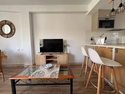 a living room with a tv and a table at Parking Privado l Terraza Relajante Junto Al Mar in Tavernes de Valldigna