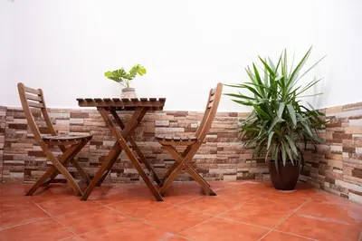 a wooden table and two chairs next to a brick wall at Apartamento a 7 minutos de la playa y cerca de la estación de autobús in Valencia