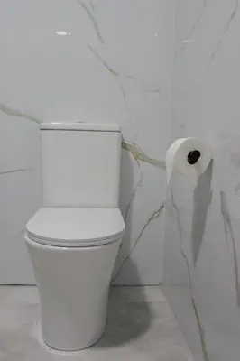 a white toilet in a bathroom with a roll of toilet paper at La plata 59 in Valencia