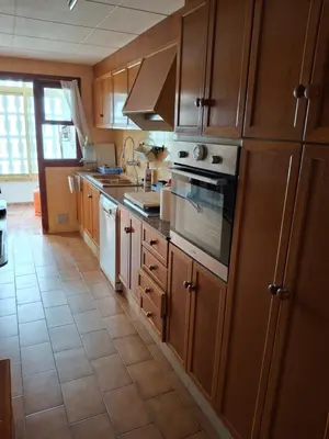 a kitchen with wooden cabinets and a tile floor at Arensol Playa de Cullera in Cullera