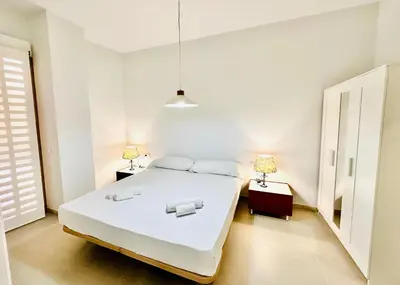 a white bedroom with a large bed and two lamps at Filologo Sanelo Luxury Apartaments in Valencia