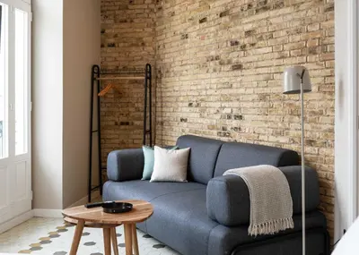 a living room with a blue couch and a brick wall at Limehome Valencia de Xativa in Valencia