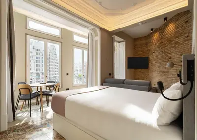 a bedroom with a large white bed and a table at Limehome Valencia de Xativa in Valencia