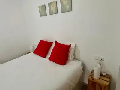 a bedroom with a white bed with red pillows at District Key - Valencia, Playa Patacona in Valencia