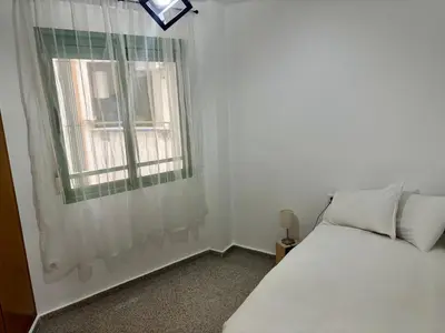 a small bedroom with a bed and a window at District Key - Valencia, Playa Patacona in Valencia