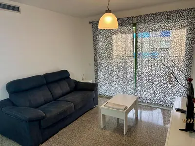 a living room with a blue couch and a table at District Key - Valencia, Playa Patacona in Valencia