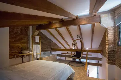 a bedroom with a large bed in a room with exposed ceilings at Cozy loft style apartment in El Cabanyal in Valencia