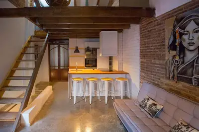 a kitchen with a bar with stools and a painting on the wall at Cozy loft style apartment in El Cabanyal in Valencia