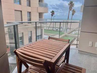 a wooden bench on a balcony with a view of the beach at Apartamento Mare Nostrum in Valencia