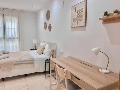 a white bedroom with a bed and a desk at Apartamento Mare Nostrum in Valencia
