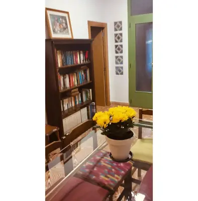 a living room with a glass table with a vase of yellow flowers at El Almazán in Buñol