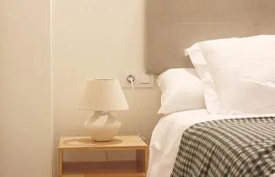 a lamp on a table next to a bed at El Apartamento in Valencia