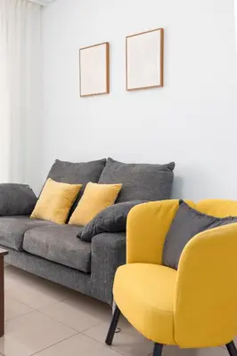 a couch and a yellow chair in a living room at ApartUP Patacona Iconic I in Valencia