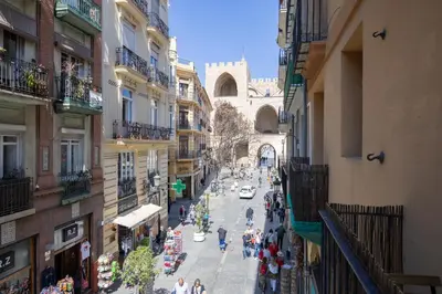 a group of people walking down a street between buildings at Apartamento 4 Pax Vistas Torres de Serrano in Valencia