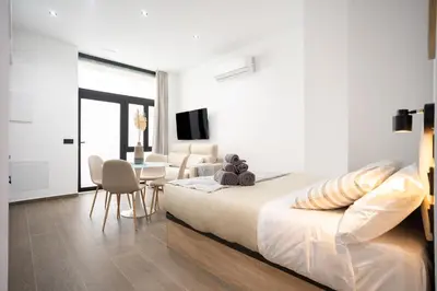 a white bedroom with a bed and a dining room at Valencia Central Flats - Exclusiva, junto al Roig Arena in Valencia