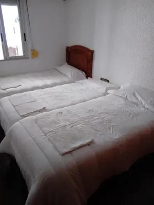 two beds in a room with white sheets and a window at Reina Beach House in Valencia