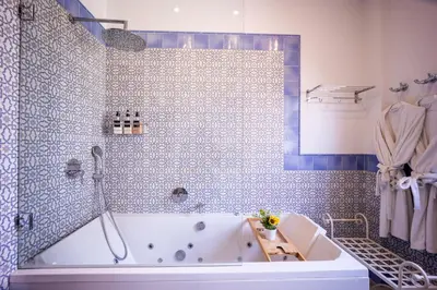 a bathroom with a tub and a blue tiled wall at Portrait Boutique Villa in Valencia