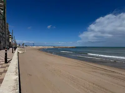 a beach with people walking on the sand and the ocean at Brisa de mar in El Perelló