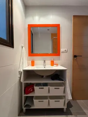 a bathroom with an orange mirror and a sink at Brisa de mar in El Perelló