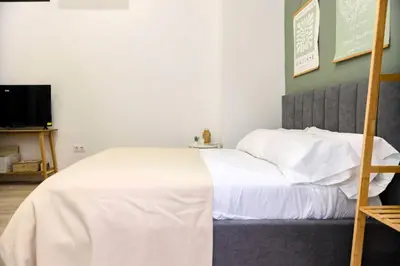 a bedroom with a bed with white sheets and a ladder at Parque de Cabecera & Bioparc Apartment in Valencia