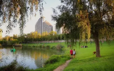 two people walking in a park next to a lake at Parque de Cabecera & Bioparc Apartment in Valencia