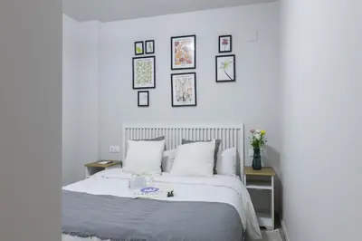 a bedroom with a white bed with pictures on the wall at El Cabañal - Familiar in Valencia