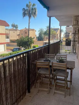 a wooden table and chairs on a balcony at Apartamento Neptuno A4 in Puebla de Farnals
