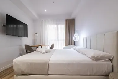 a bedroom with a large white bed and a table at Lôla Suites by Concept Flats in Valencia