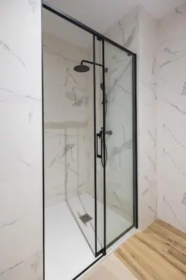 a glass shower in a bathroom with white marble walls at Lôla Suites by Concept Flats in Valencia