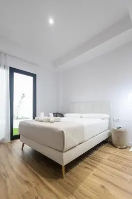 a white bedroom with a large bed and a wooden floor at Lôla Suites by Concept Flats in Valencia